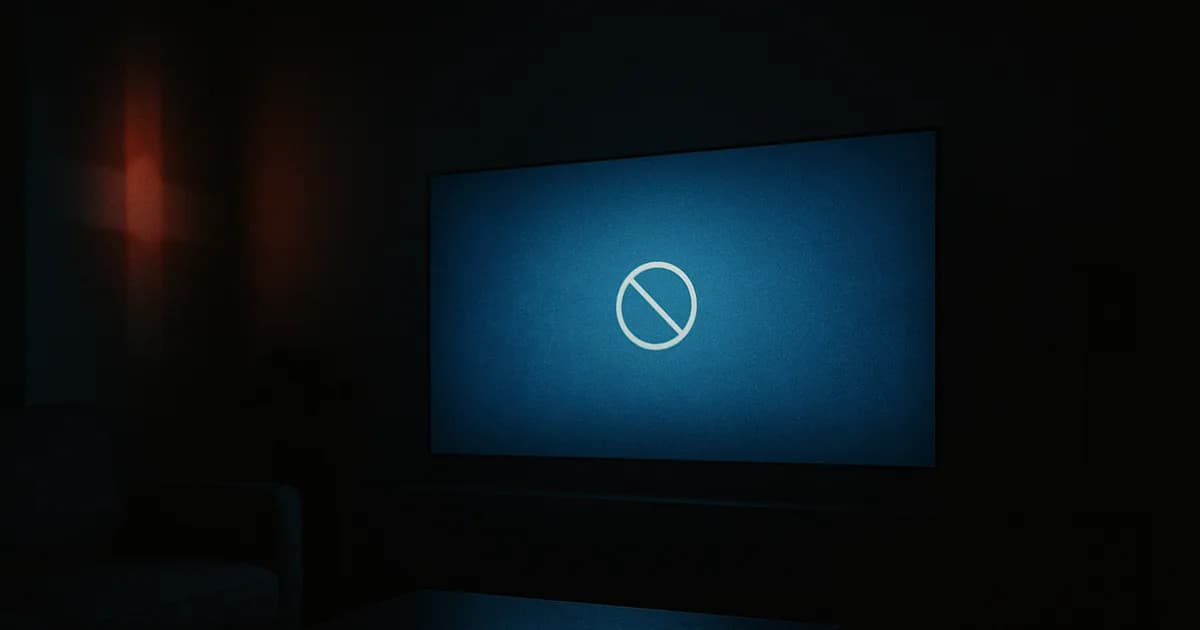 Mørkt dansk stuebillede om aftenen, hvor et stort tv lyser med en kold blå fejlskærm, der antyder en blokeret streamingtjeneste, med en fjernbetjening på et mørkt sofabord.